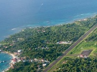 Aerial view of a lush coastal area with a runway adjacent to a turquoise bay.