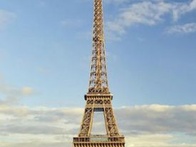 A view of the Eiffel Tower standing tall against a clear blue sky, surrounded by green trees.