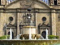 A historic cathedral with a fountain in front under a clear blue sky.