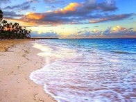 A serene beach at sunset with gentle waves and a colorful sky.