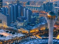 Aerial view of a modern city at twilight with a distinctive sphere-shaped tower and snow-covered paths.