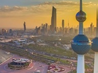 Aerial view of Kuwait City skyline showcasing iconic Kuwait Towers and modern skyscrapers during sunset.