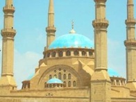 A large mosque with four minarets and a blue dome under a clear sky.