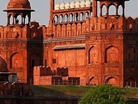 A photo of the Red Fort, an iconic Mughal-era fortress with a waving Indian flag, under a clear sky.