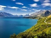 A scenic view of a blue lake beside a mountainous landscape with a clear sky.