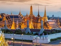 A scenic view of the Grand Palace in Bangkok, Thailand at dusk, showcasing its golden spires and traditional architecture.