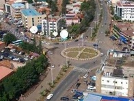 Aerial view of a bustling urban center with multiple buildings, roads, and a roundabout with statues