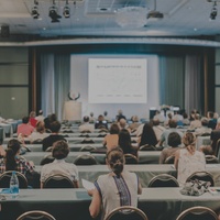 A large audience attending a presentation in a conference room.
