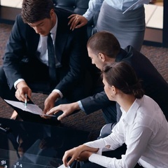 A group of professionals is discussing document details in a modern office setting.