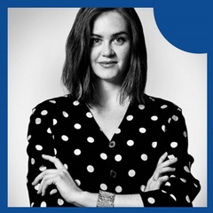 A black and white portrait of a woman in a polka dot blouse with her arms crossed.