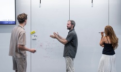 Three people are engaged in a collaborative discussion in a modern workspace.