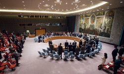 A large group of delegates is gathered in a circular chamber for a meeting.