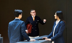 A business meeting is taking place at a reception desk with three professionals engaged in conversation.
