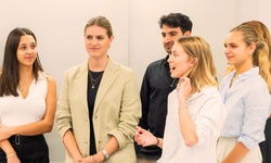 A group of young professionals engaged in conversation in a modern office setting.