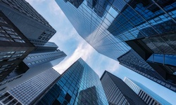 A view looking up at tall skyscrapers reflecting blue skies.