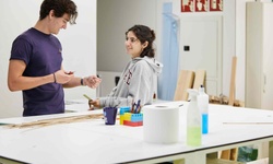 Two students are engaged in a creative project in a bright classroom.