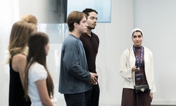 A group of young people are engaged in a discussion in a modern setting.