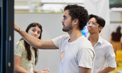 A group of three young people engaged in a collaborative activity in a modern workspace.