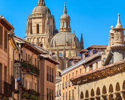 A picturesque view of historic buildings and cathedral domes under a clear blue sky.