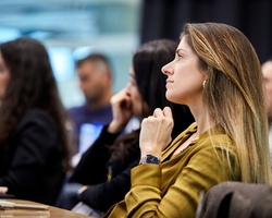 A woman thoughtfully listening in a classroom setting.