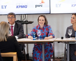A panel of professionals discussing in a conference setting.
