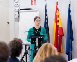 A woman is speaking at a podium in a conference setting.