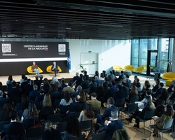 A professional event taking place in a modern auditorium with an audience present.