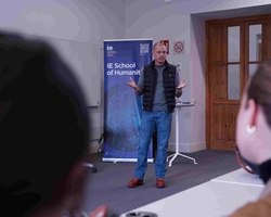 A speaker presenting in front of an audience at an educational institution.