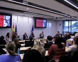 A panel discussion taking place in a conference room with various attendees and speakers.