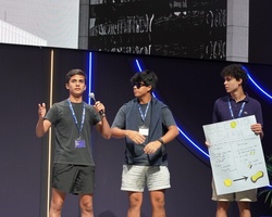A group of young people presenting on stage with a poster.