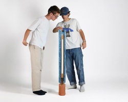 Two young men examining a large T-shaped sculptural object in a studio setting