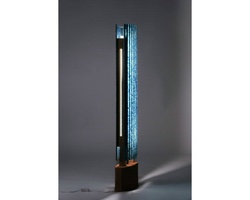 A modern art installation featuring a tall, slender structure with blue lights embedded within, set against a gray background.