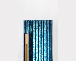 A book with a textured blue cover partially hidden behind a white surface.