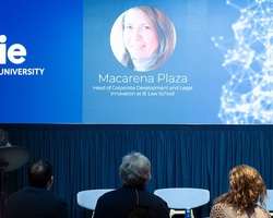 A woman is speaking at a podium in front of a presentation screen at an educational event.