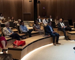 A panel discussion taking place in a modern auditorium with an audience.