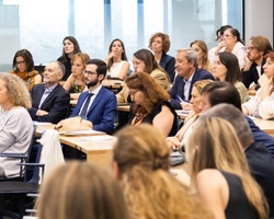 A group of professionals sitting in a conference room listening to a presentation.