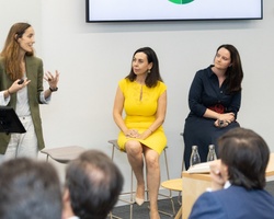 Three women engaging in a presentation to an audience in a modern office setting.