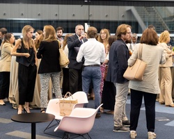 A group of people networking at an indoor event with modern furniture and large windows.