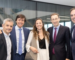 Five professionals, four men and one woman, smiling in a modern office environment.