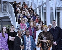 A diverse group of women posing together on a staircase in a modern building.