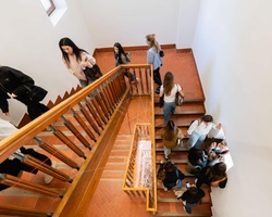 A group of people interacting near a staircase in a well-lit space.
