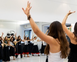 A group of women is dancing in a studio with mirrors.