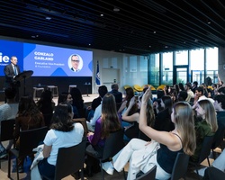 A speaker addresses an audience at an event in a modern venue.