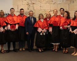 A group of people dressed in formal academic regalia standing in a room.