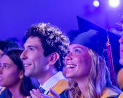 A group of graduates celebrating at a ceremony with smiles and excitement.