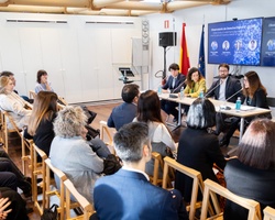 A group of people attentively participating in a panel discussion in a well-lit conference room.