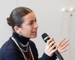 A woman speaking into a microphone during a presentation or meeting.