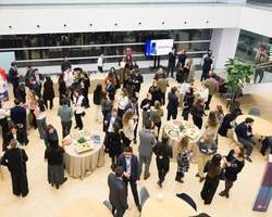 A crowded indoor event showcasing people mingling around tables with various refreshments.