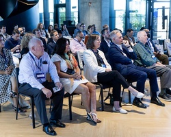 A diverse audience is attentively listening to a presentation in a modern venue.