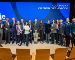 A group of people standing in a conference room with a blue background screen displaying text.